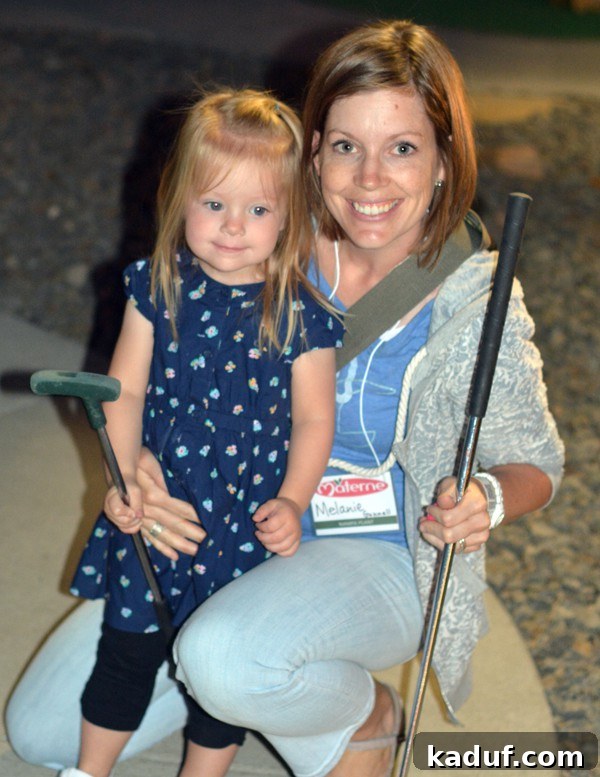 A Mom and daughter holding putt putt golf clubs. 