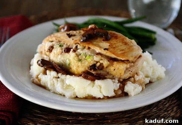 Olive Garden-Style Stuffed Chicken Marsala 3 A perfectly cooked stuffed chicken breast rests on a bed of fluffy mashed potatoes, accompanied by vibrant green beans on a pristine white plate, showcasing a delightful meal.