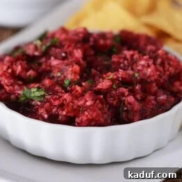 A small ramekin of fresh cranberry salsa with tortilla chips.