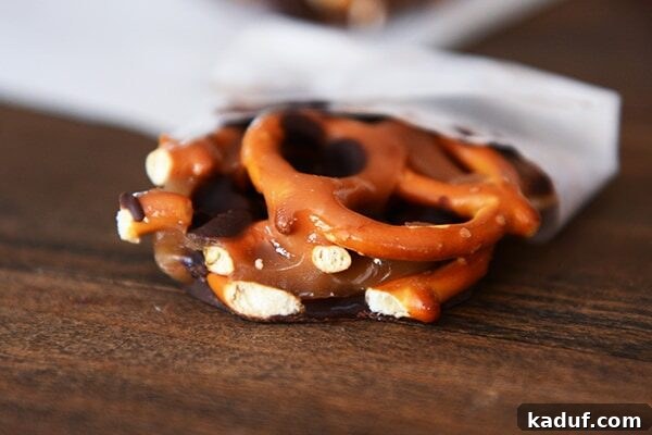 Sweet and Salty Dark Chocolate Caramel Pretzel Bark 3 A beautifully crafted chunk of dark chocolate caramel pretzel bark resting on a piece of parchment paper, highlighting its layers.
