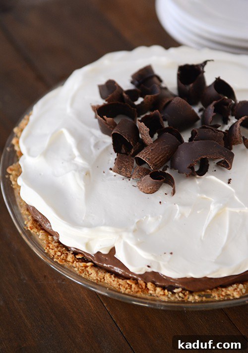 Salty Sweet Chocolate Pretzel Pie 4 A beautifully garnished chocolate pudding pie with whipped topping and chocolate curls, set in a clear glass pie dish.