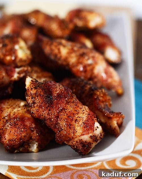Crispy Bacon Wrapped Chicken Bites 2 A white platter of bacon-wrapped chicken bites, showcasing their golden-brown, crispy exterior.