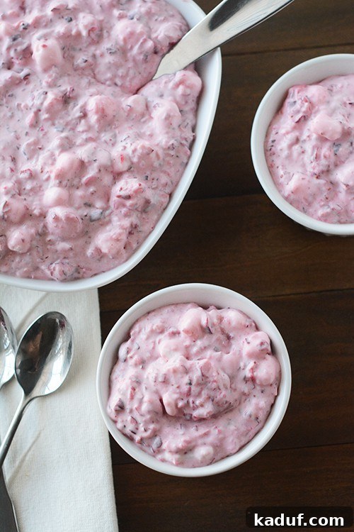 Luscious Cranberry Cloud 2 Top view of a big dish and two smaller bowls of cranberry fluff salad, showcasing its creamy, pink texture.