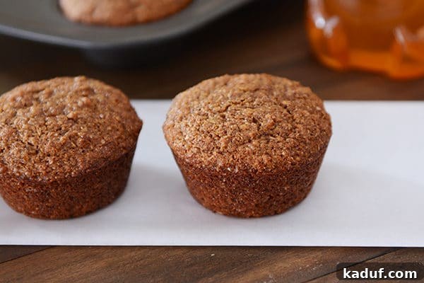 Hearty Honey Bran Muffins 4 Two perfectly golden brown whole grain honey bran muffins presented side-by-side, showcasing their appealing rustic crust.