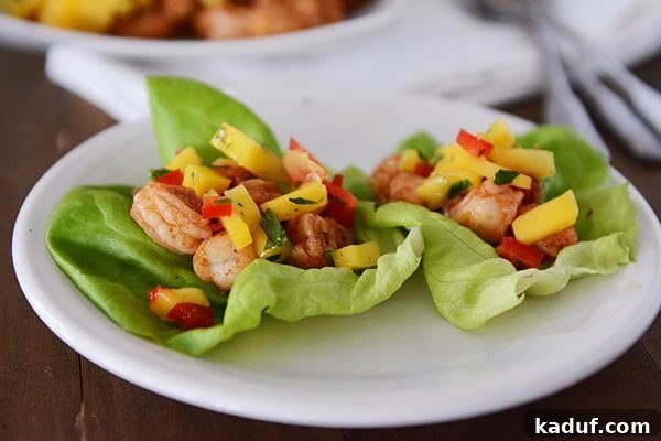 Tropical Shrimp Mango Lettuce Wraps 3 Two perfectly portioned shrimp and mango lettuce wraps nestled side-by-side on a clean white plate, ready to be enjoyed.