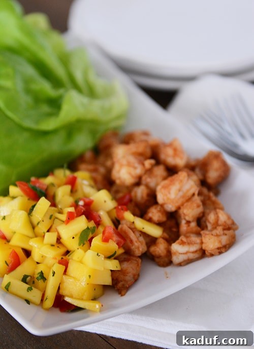 Tropical Shrimp Mango Lettuce Wraps 4 A clean white platter showcases perfectly cooked shrimp on one side and a vibrant, freshly chopped mango salsa on the other.