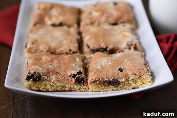 S'mores Cookie Bars 5 A white platter adorned with neatly cut meringue-topped chocolate chip bars, ready for serving.
