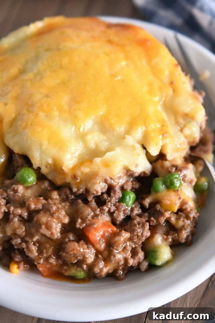 Lamb and Potato Comfort 8 A hearty serving of Shepherd's Pie in a white bowl, showcasing the rich beef and vegetable mixture under a fluffy, cheesy potato topping.
