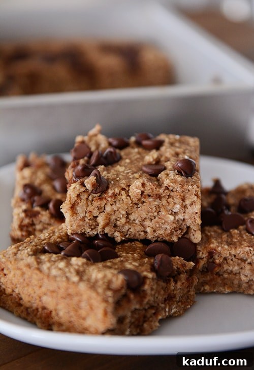 Banana Bread Oatmeal Chocolate Chip Bars 2 A white plate with four banana oat chocolate chip bars, showcasing their moist texture.