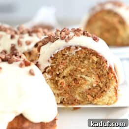Marbled Carrot Bundt with Cream Cheese Bliss 13 A slice of carrot and cream cheese swirled bundt cake being taken off a white plate with a white spatula.