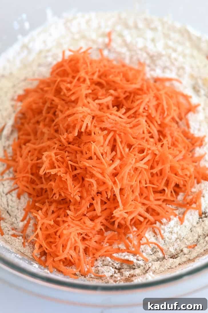 Marbled Carrot Bundt with Cream Cheese Bliss 5 Top down view of a glass bowl with a carrot cake flour mixture and shredded carrots.
