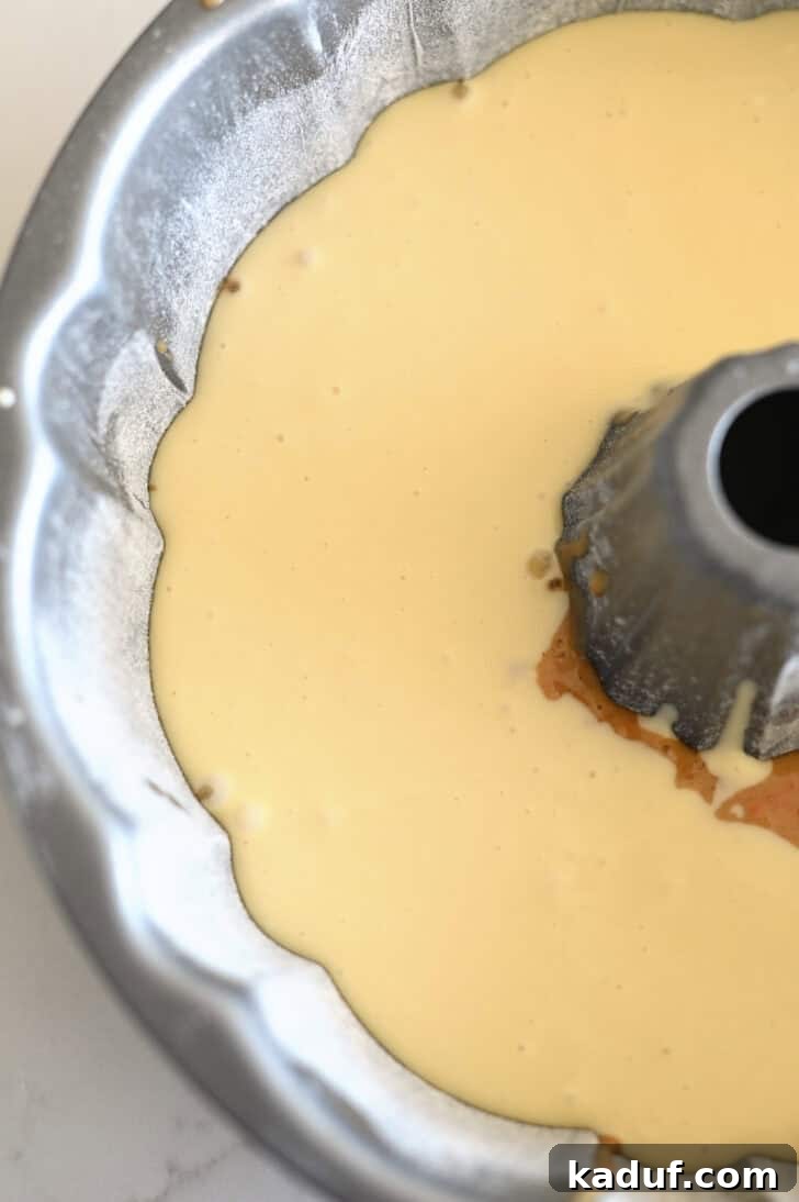 Marbled Carrot Bundt with Cream Cheese Bliss 8 Top down view of a greased and floured bundt cake pan with a raw carrot cake and cream cheese batter.
