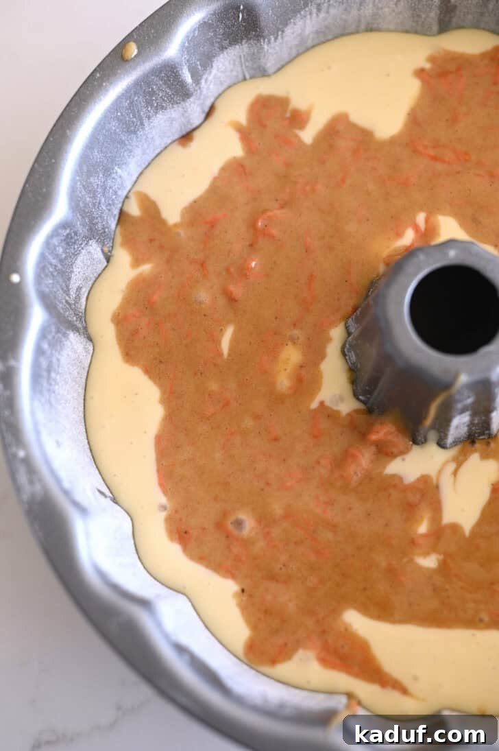 Marbled Carrot Bundt with Cream Cheese Bliss 9 Top down view of a greased and floured bundt cake pan with a raw carrot cake and cream cheese batter.