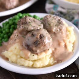 Creamy Skillet Swedish Meatballs 11 Three meatballs on top of pile of mashed potatoes smothered in thick brown gravy.