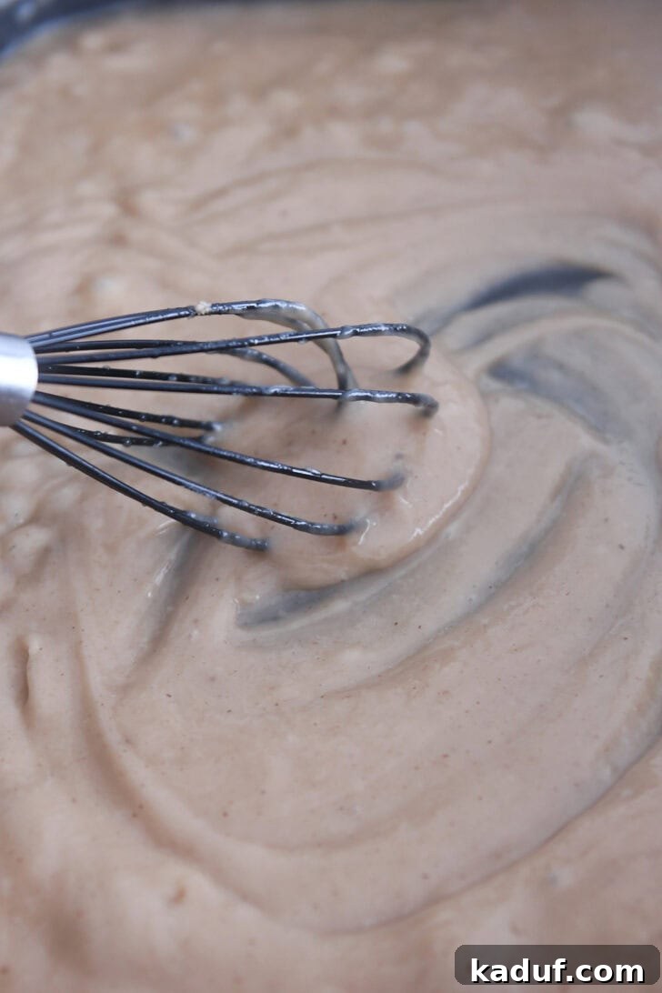 Creamy Skillet Swedish Meatballs 6 Rich, thick brown gravy being smoothly whisked in an electric skillet, ensuring a lump-free and perfectly creamy consistency for the Swedish meatballs.