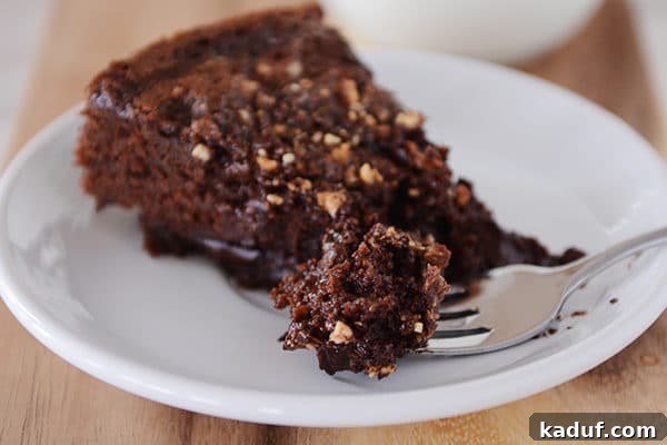 A slice of fudgy chocolate cake with a bite being taken out, revealing the rich, moist interior and the melted chocolate chip layer.