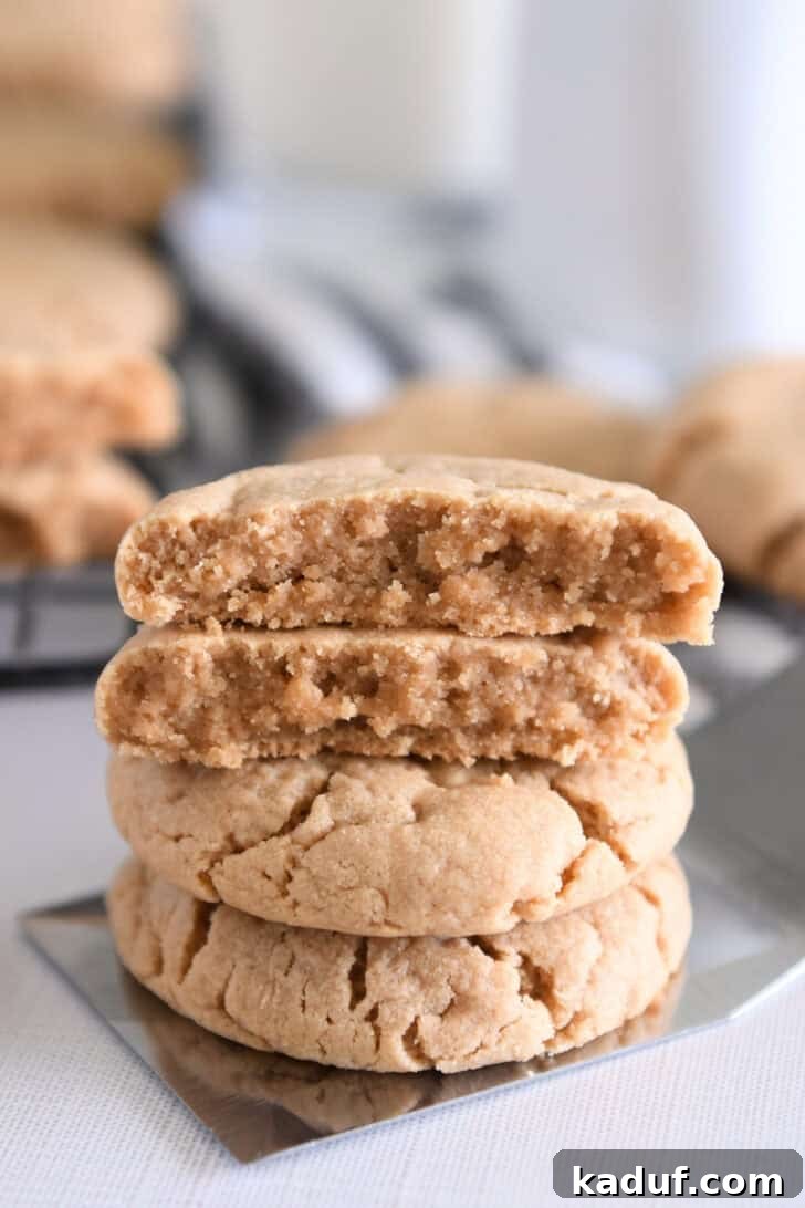 Irresistible Peanut Butter Cookies 2 Four stacked peanut butter cookies on flat metal spatula, showcasing their perfect texture and golden-brown finish.