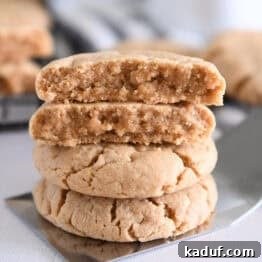 Four stacked peanut butter cookies on flat metal spatula.