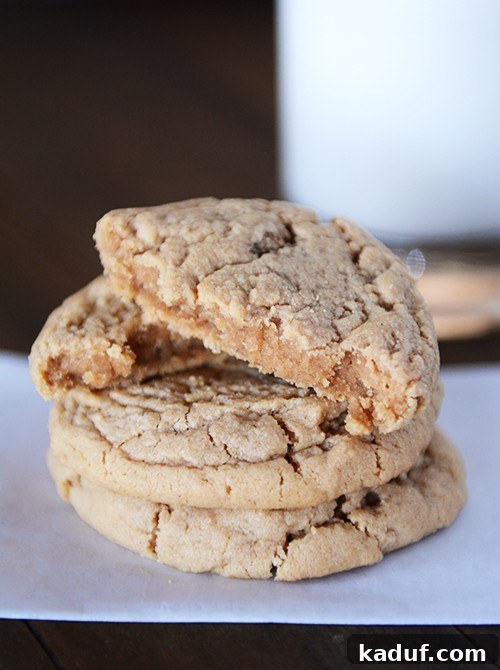 Irresistible Peanut Butter Cookies 13 A stack of peanut butter cookies with the top cookie split in half, revealing its soft and chewy interior.