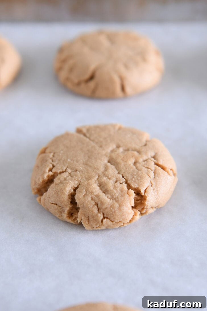 Irresistible Peanut Butter Cookies 9 Freshly baked peanut butter cookie on white parchment paper, showcasing its perfect round shape and golden color.