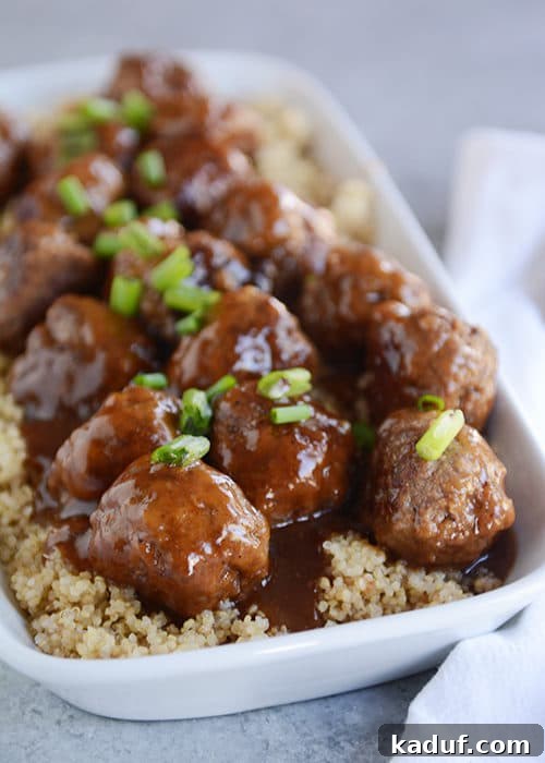 Sweet & Sticky Skillet Teriyaki Meatballs 3 A white casserole dish filled with fluffy rice, generously topped with an abundance of teriyaki-glazed meatballs, creating a mouth-watering presentation.