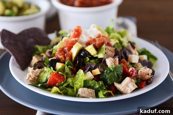A close-up view of the Mexican chopped salad served on a white plate, showcasing the diverse ingredients like chicken, cheese, and colorful vegetables, all perfectly diced and mixed.