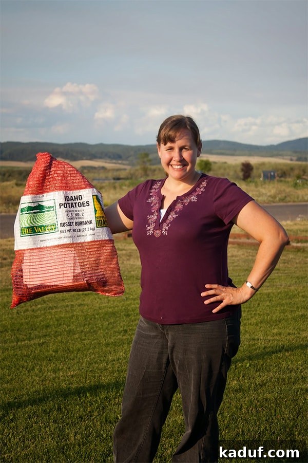 A determined woman, holding a heavy sack of potatoes, posing outdoors. She is dressed in running gear, possibly preparing for a challenge or symbolizing strength.