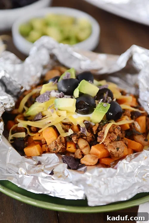 Foil Roasted Sweet Potato Tacos 4 An open tinfoil packet of cooked sweet potato tacos toped with cheese, sour cream, avocado dices, and slices olives. A complete and inviting meal ready to be enjoyed.