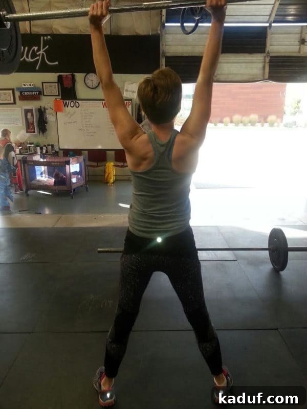 The Rachelle Narrative 3 A lady lifting a barbell of weights over her head.