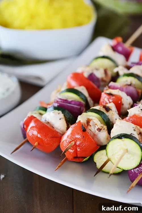 Juicy Greek Chicken Skewers with Refreshing Tzatziki 2 A white platter with grilled chicken and vegetable Greek kebabs.