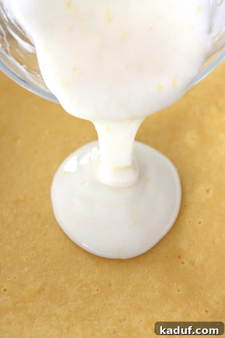 Mini Lemon Brownie Delights 5 A glass bowl pouring a thick white lemon glaze over a pan of golden-baked lemon bars, demonstrating the glazing process with a smooth, even flow.