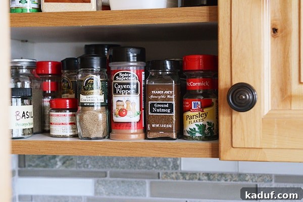 My Spice Cabinet Unveiled 3 An array of spice jars neatly arranged within a kitchen cupboard, ready for cooking.