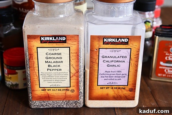 My Spice Cabinet Unveiled 5 Large, bulk containers of coarse black pepper and garlic powder side-by-side on a kitchen counter.