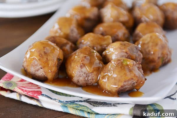 Sticky Zesty Orange Meatballs 5 A white platter of meatballs with an orange glaze poured over the top.