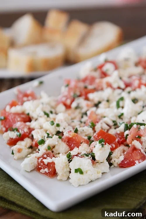 Effortless Greek Feta Perfection 2 A white tray of Greek feta dip with sliced baguettes in the background.