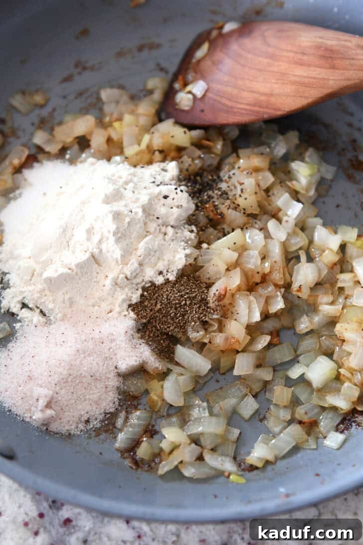 Rustic German Potato Salad 3 Top down view of a skillet with spices, sautéed onions, and flour, showing the initial stages of preparing the tangy dressing base.