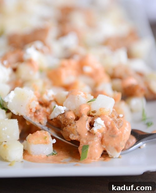 Vibrant Roasted Red Pepper Pesto Hash Browns 3 A white tray full of cubed potatoes covered in a red pepper sauce.