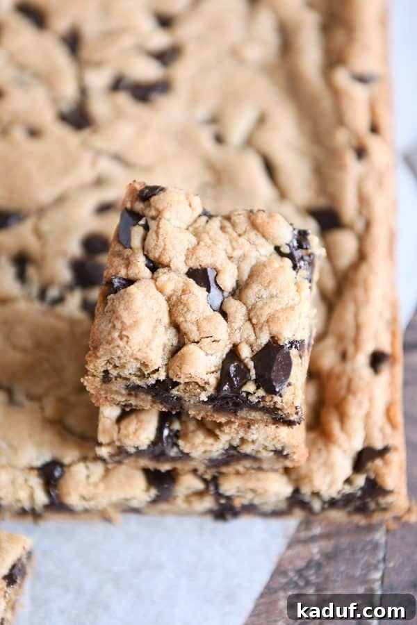 Decadent Thick and Chewy Chocolate Chip Cookie Bars 2 Two chocolate chip cookie bars stacked on a white surface, showcasing their thick, chewy texture and abundant chocolate chips.