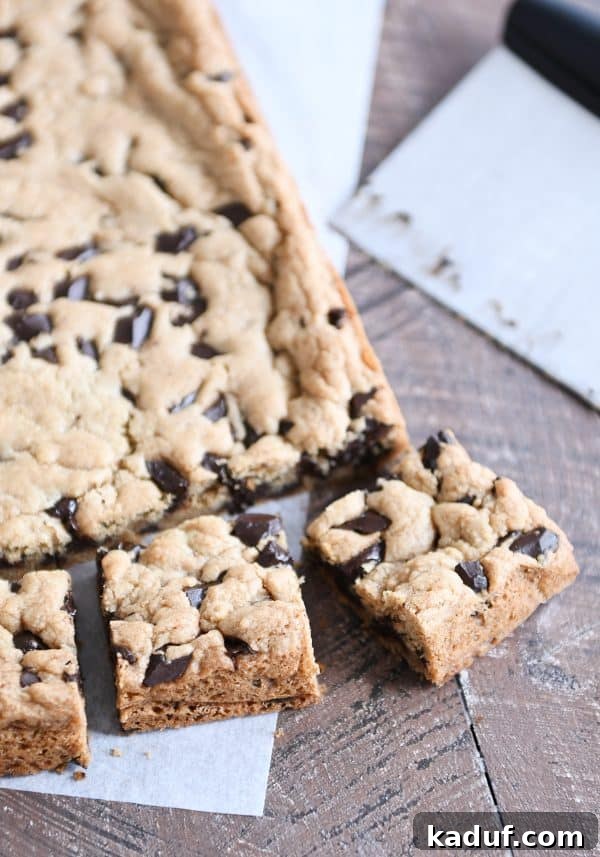 Decadent Thick and Chewy Chocolate Chip Cookie Bars 3 A generous slab of freshly baked chocolate chip cookie bars, perfectly cut into squares, ready to be enjoyed.