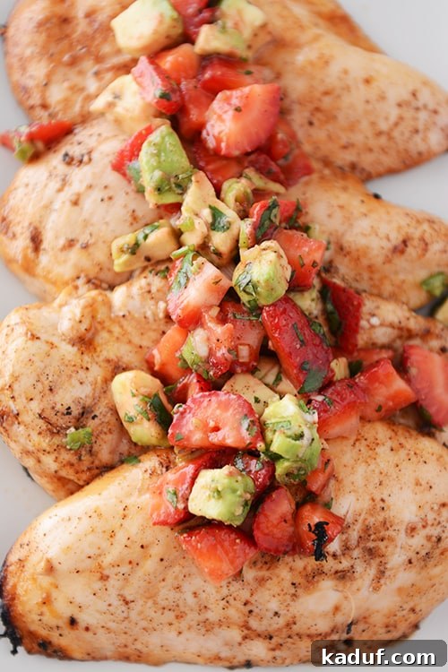 Four large grilled chicken breasts topped with a strawberry-avocado salsa.