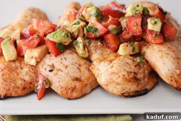 Four grilled chicken breasts topped with a strawberry-avocado salsa.