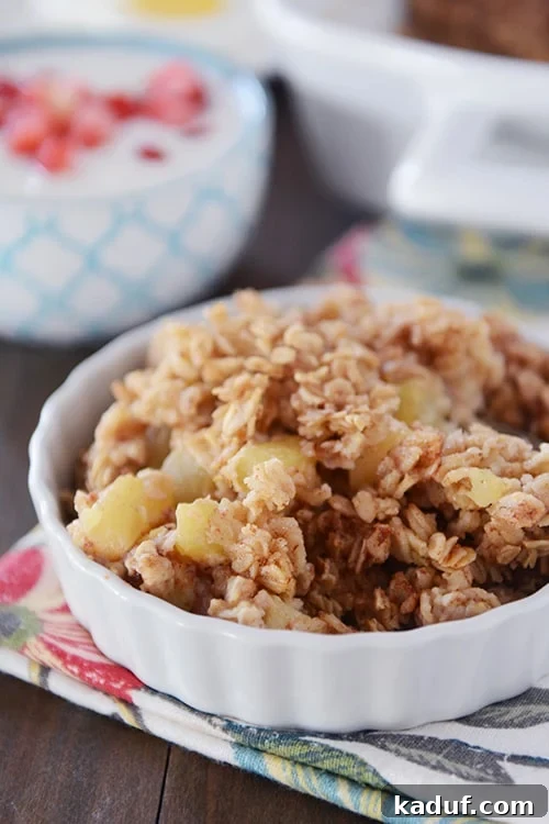 Homestyle Apple Cinnamon Baked Oatmeal 2 A small white bowl of baked oatmeal with chunks of cinnamon-coated apples, ready to be enjoyed.
