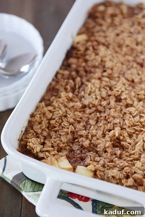 Homestyle Apple Cinnamon Baked Oatmeal 4 A white dish full of baked oatmeal with tender chunks of apple peeking out from the front of the dish.