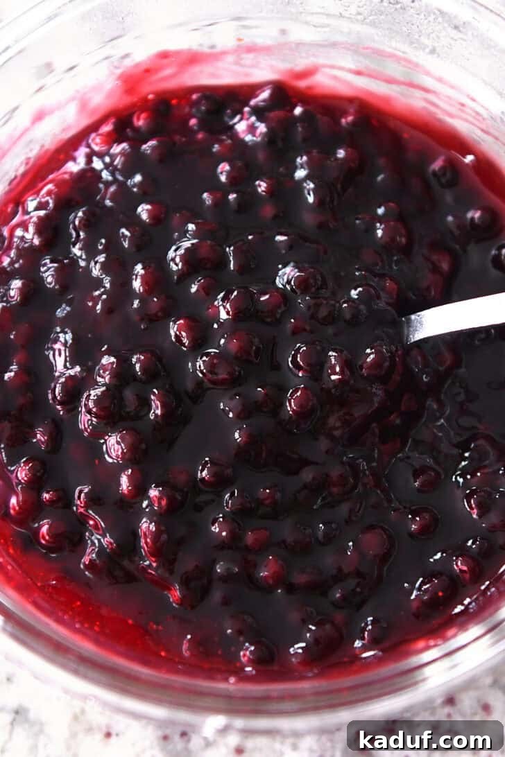 Ultimate No-Bake Cheesecake 7 Top down view of a rich, vibrant blueberry fruit sauce in a clear glass bowl, glistening and ready to be served.