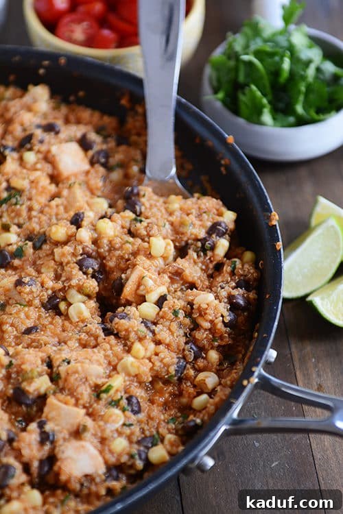 Effortless Skillet Quinoa Enchiladas 2 A large metal spoon taking a generous helping of a vibrant quinoa enchilada black bean meal out of a rustic skillet.