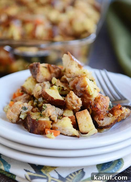 Pretzel and Sausage Stuffing Bake 3 A white plate showcasing a serving of pretzel roll sausage stuffing, with a fork resting beside it.