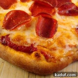 Homemade pizza with pepperoni and melted cheese on a wooden board.
