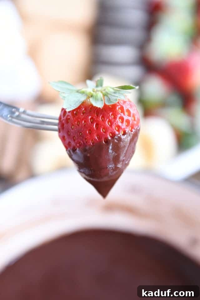 Decadent Chocolate Fondue 2 Chocolate dipped strawberry on a fondue fork, signaling a delightful dessert experience.