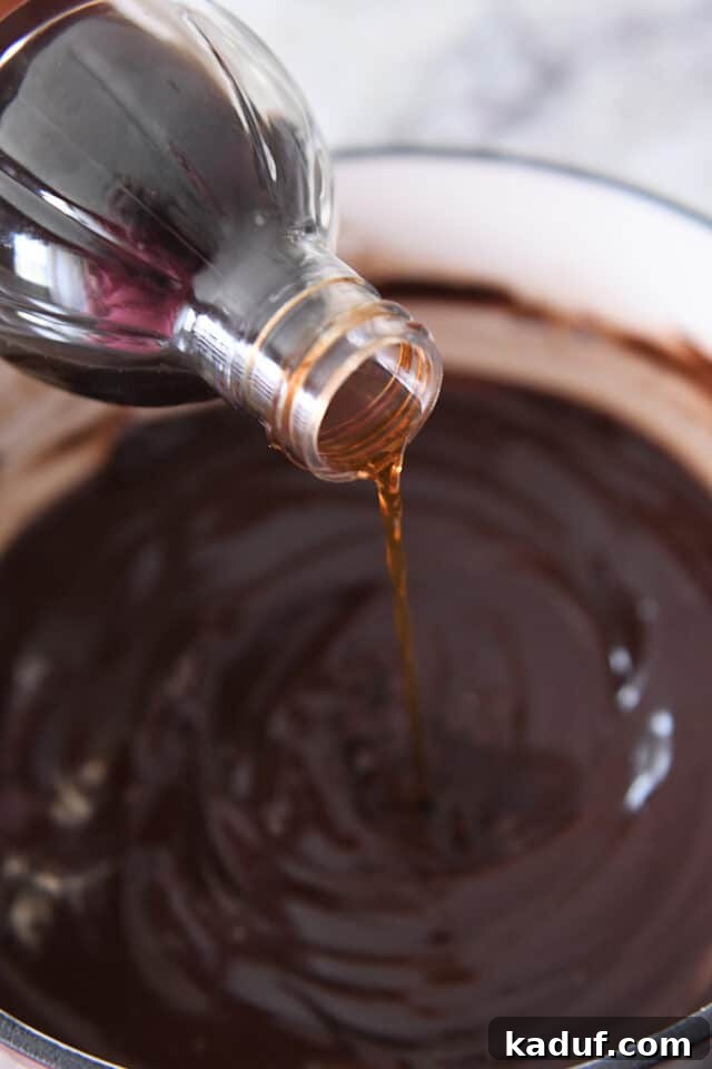 Decadent Chocolate Fondue 5 Pouring vanilla extract into the rich chocolate fondue, adding the finishing touch.