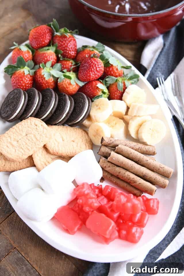 Decadent Chocolate Fondue 7 An array of delicious dippers including Oreos, strawberries, bananas, marshmallows, and pirouette cookies on a white tray.